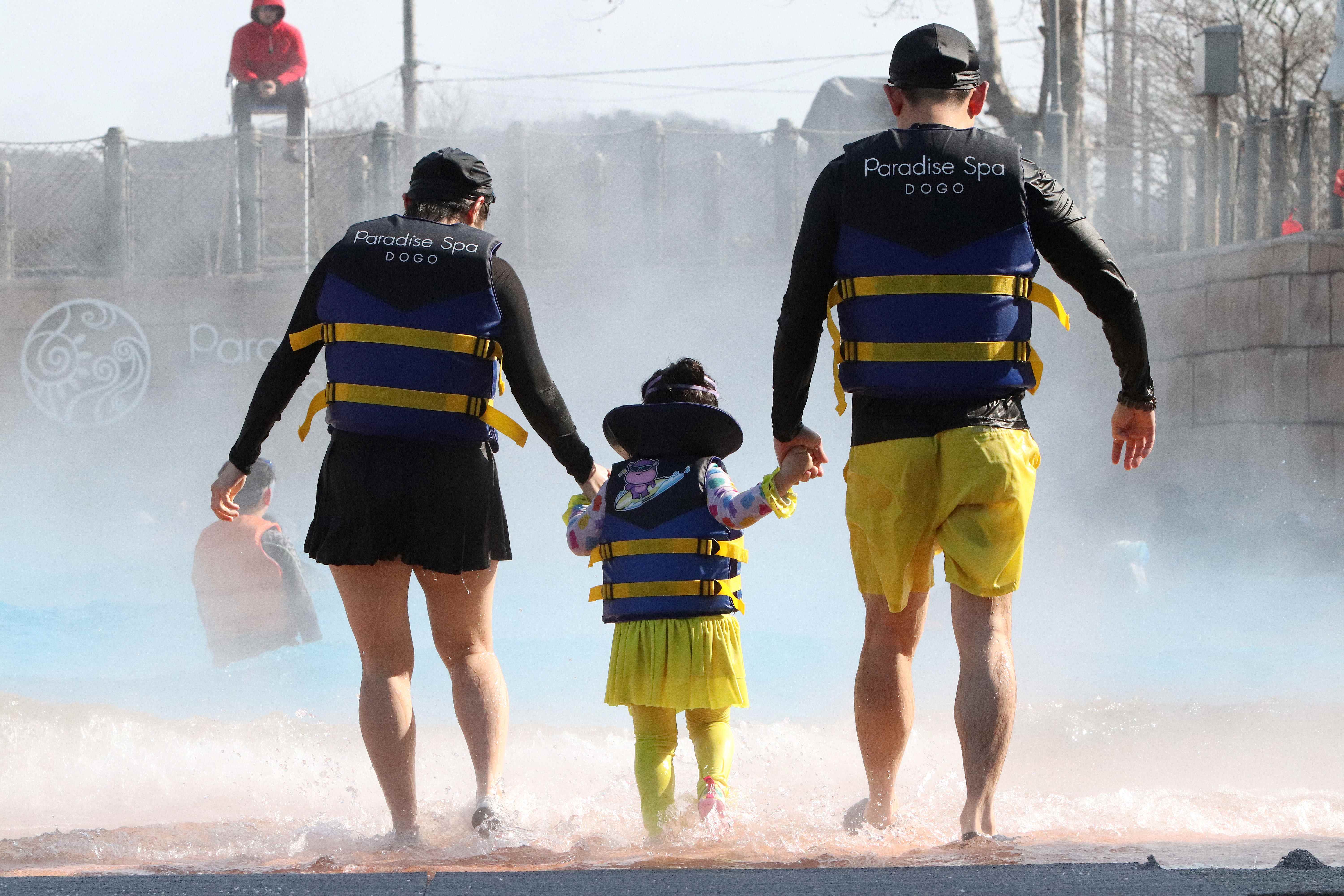 겨울철 추위를 잊고 따뜻한 온천에서 즐거운 시간을 보내는 가족의 뒷모습.