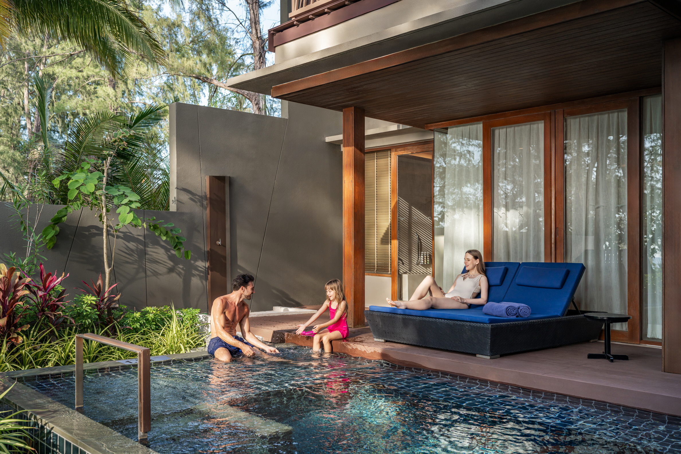 열대 정원 속 개인 수영장에서 여유로운 휴가를 즐기는 가족의 모습.